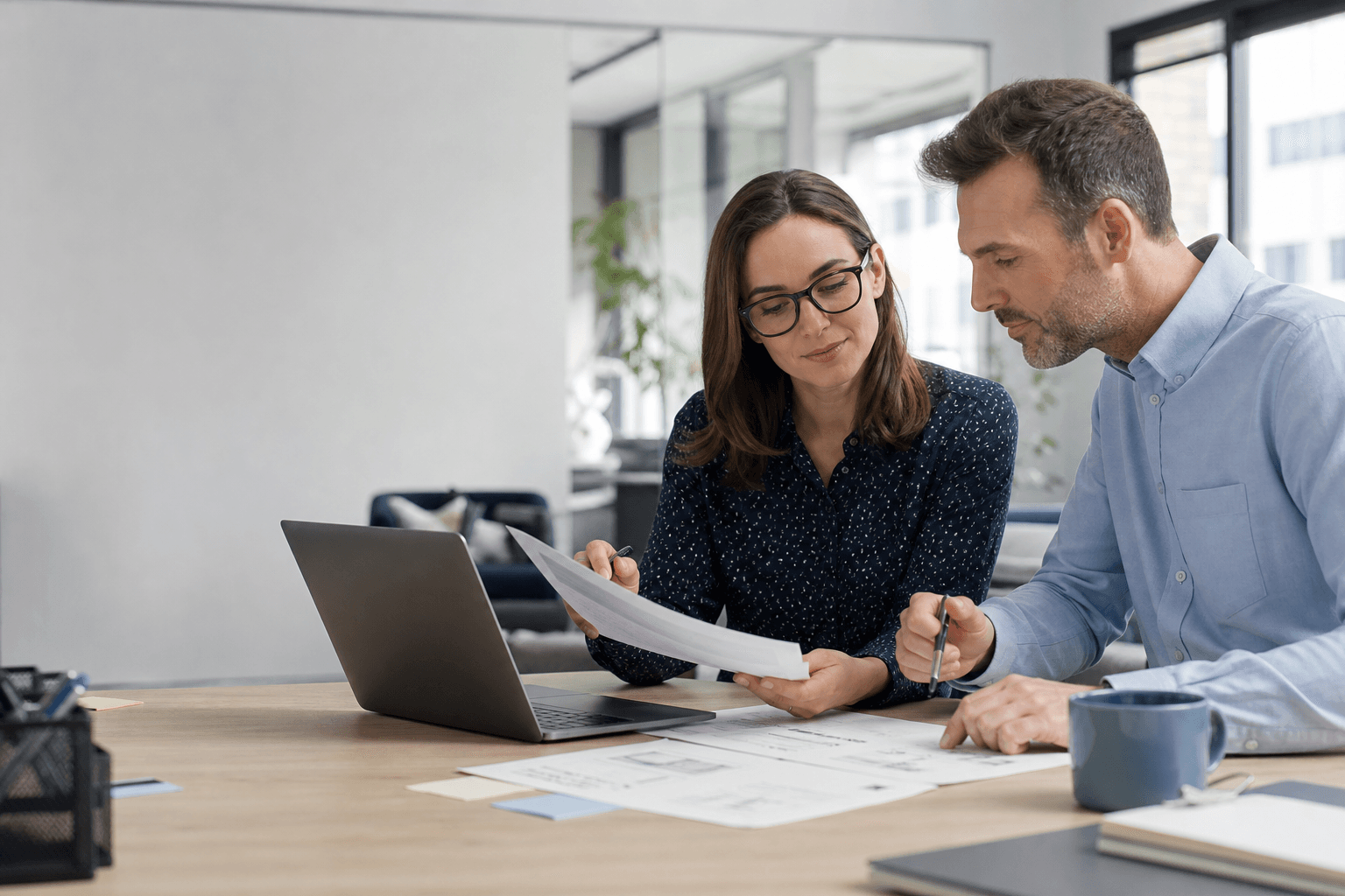 Consultant and technical writer collaborating on documents at a modern office desk